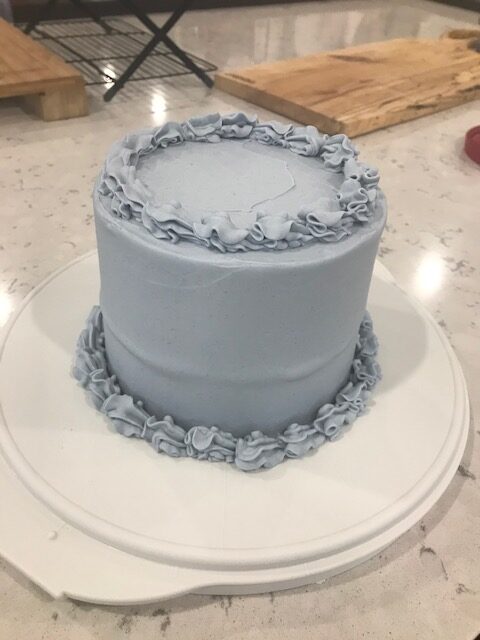 Picture of the finished cake that debuted the Raspberry Cake recipe. Frosted cake with ruffle borders in a periwinkle colour.